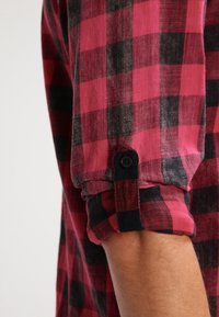 Rood en zwart geblokt shirt met opgerolde mouwen, voorzien van een enkele knoopmanchet, gemaakt van textuurstof.