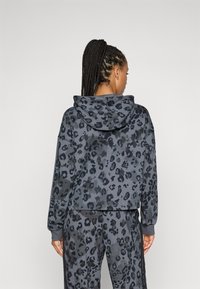 Sweatshirt com capuz cortado em cinza escuro, apresentando um padrão de estampa de leopardo em vários tons de preto. Textura suave com punhos canelados.