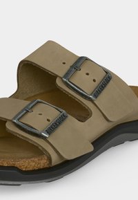Ταμπά σανδάλι Birkenstock με δύο ρυθμιζόμενες μεταλλικές αγκράφες και φελλό πάτο σε μαύρη καουτσούκ σόλα.