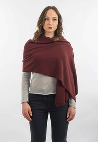 Burgundské šál vyrobený z měkké tkaniny, ovinutý kolem ramen, s draped designem; nošený přes světle šedý svetr a tmavé kalhoty.
