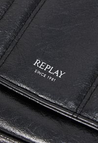 Billetera de cuero negro texturizado con el logo en relieve "REPLAY SINCE 1981" en plata. Patrón arrugado distintivo con detalles de costura visibles.