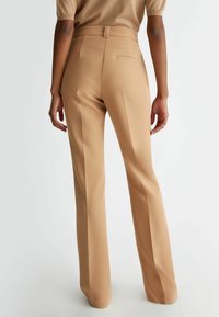 Beige op maat gemaakte broeken met een aansluitende taille, taps toelopende benen en een gladde textuur. Heeft een achterzak en een strakke, minimalistische uitstraling.