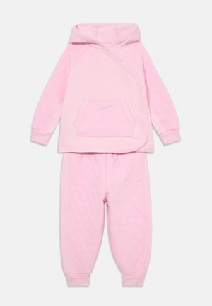 Haut à capuche matelassé rose avec une poche avant, fermeture à pression et logo. Pantalons matelassés assortis avec une ceinture élastique et un logo sur le côté.