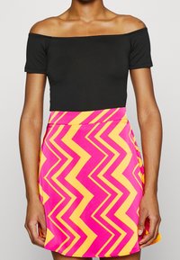 Black off-the-shoulder top paired with a pink and yellow zigzag patterned skirt. The skirt features a fitted waist and flared hem.