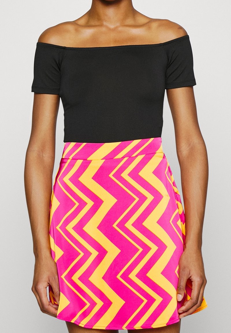 Black off-the-shoulder top paired with a pink and yellow zigzag patterned skirt. The skirt features a fitted waist and flared hem.