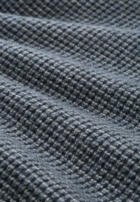 Gewebter Stoff in dunkelgrauen und hellgrauen Tönen mit einem karierten Muster, einer strukturierten Oberfläche und einem weichen Gewebe.