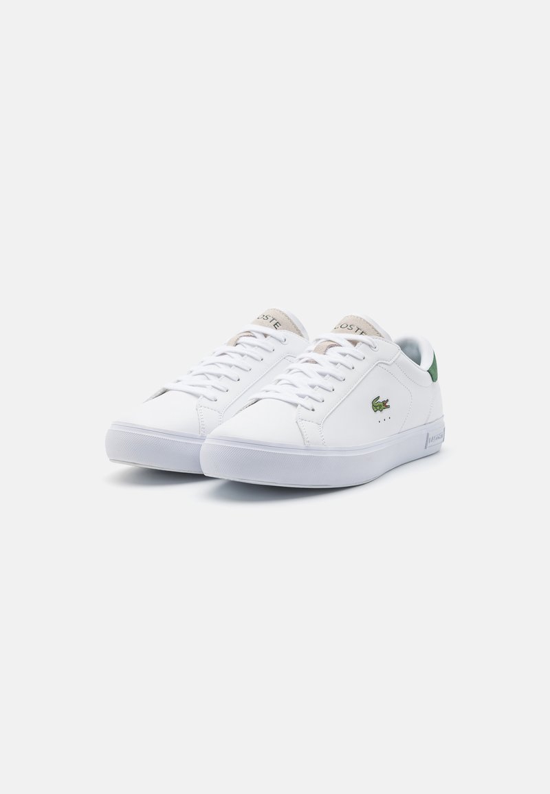 Witte sneakers met een gladleren bovenkant, groene accenten op de hiel en een gestructureerde rubberen zool. Lacoste-logo aan de zijkant.