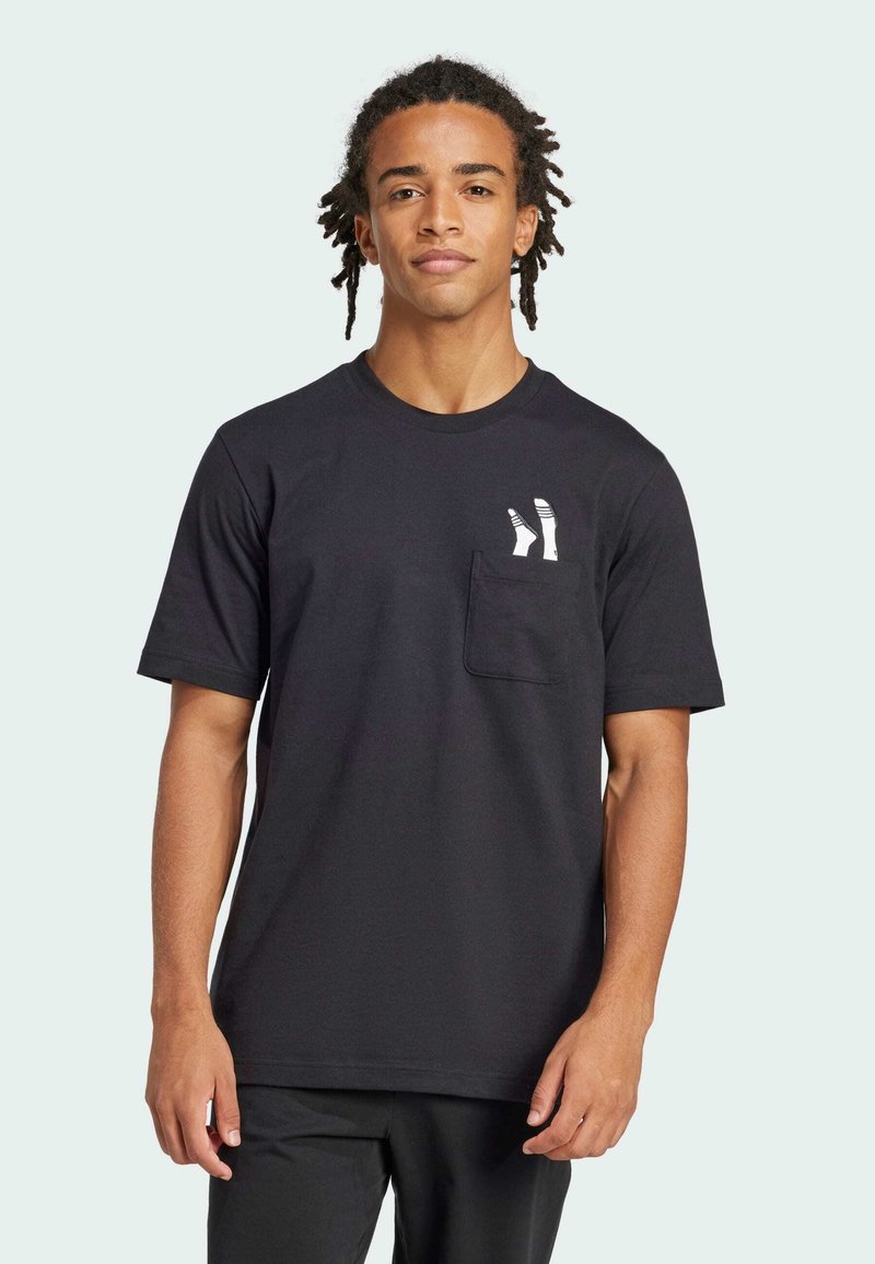 Μαύρο βαμβακερό μπλουζάκι με κοντό μανίκι, στρογγυλή λαιμόκοψη και τσέπη στο στήθος που διαθέτει μια λευκή, στυλιζαρισμένη γραφική απεικόνιση κάλτσας. Λείος υφασμάτινος ιστός.