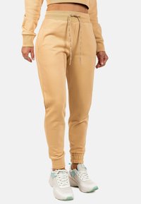 Lichtbeige joggers gemaakt van een zachte katoenmix, met een elastische tailleband met trekkoord, zijzakken en geribbelde boorden.
