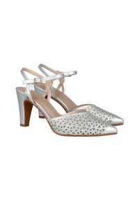 Zapatos de tacón plateados con punta afilada, que presentan una parte superior de tela con diseño de encaje y correas en el tobillo. El tacón mide aproximadamente 3 pulgadas de alto.