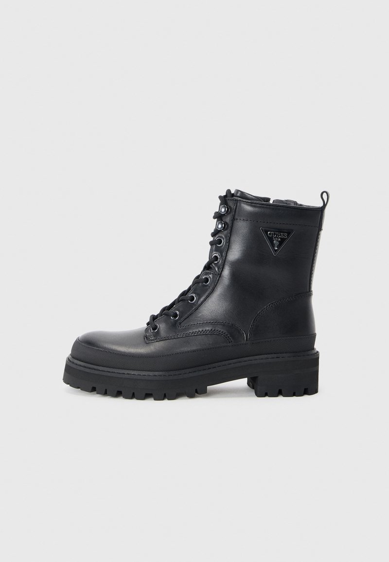 Bottines en cuir noir avec une semelle épaisse, fermeture à lacets à l'avant et un accent de marque près du haut. Elles présentent une construction robuste et une texture lisse.