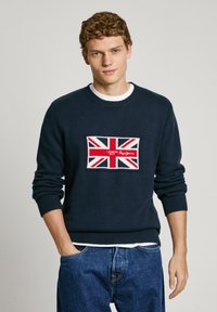 Navy sweater made of knit fabric featuring a Union Jack patch with red, white, and blue colors, round neckline, and ribbed cuffs and hem.