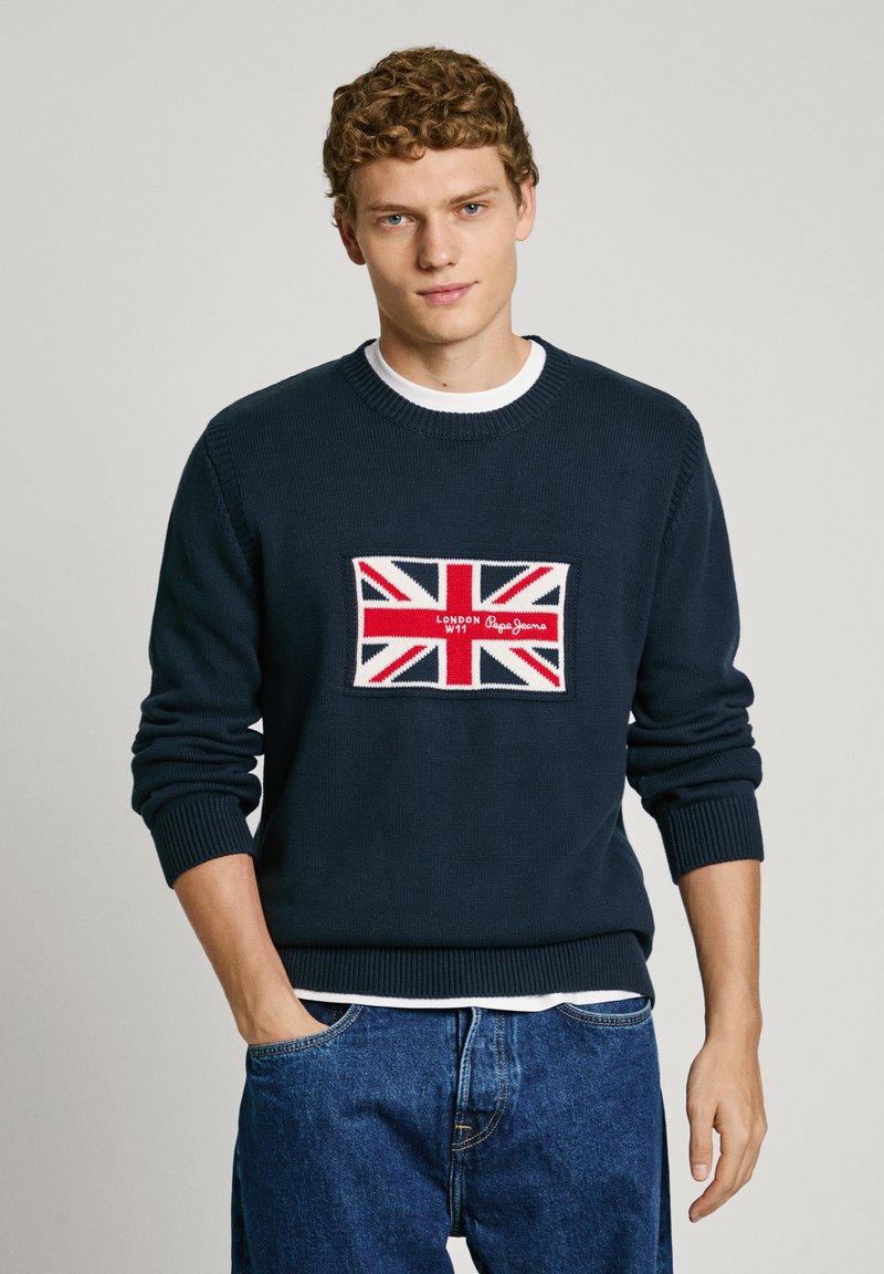 Navy sweater made of knit fabric featuring a Union Jack patch with red, white, and blue colors, round neckline, and ribbed cuffs and hem.