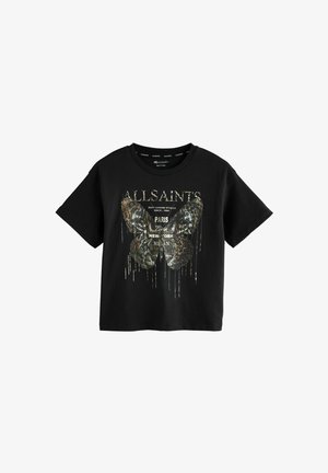 T-shirt en coton noir arbore un grand motif de papillon avec un design texturé et à motifs. Le texte à l'avant inclut le nom de la marque et le nom de la ville en couleurs métalliques.