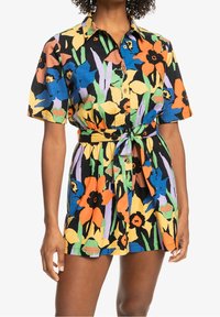 Kortärmad skjortklänning i svart tyg med ett färgglatt blommönster av orange, blå och gula blommor, åtdragen i midjan.