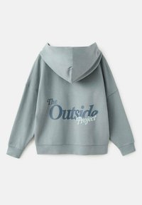 Felpa azzurra chiara con vestibilità ampia, caratterizzata da una grande grafica che recita "Il Progetto Esterno" in blu scuro sul retro e un cappuccio spazioso.