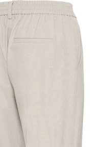 Pantalon gris clair en tissu doux, avec une ceinture élastique et une poche arrière unique. Texture lisse avec peu de détails.