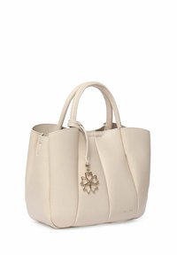 Beige neplederen handtas met verticale plooien, dubbele handvatten en een decoratieve gouden charme in de vorm van een bloem. Compacte, gestructureerde vormgeving.
