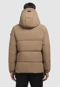 Beige gewatteerde jack met een grote capuchon, voorzien van een gequiltde structuur en elastische manchetten. Minimalistisch ontwerp met een klein logo op de rug.