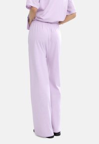 Jasnofioletowe spodnie szerokie z elastycznym paskiem w pasie, wykonane z miękkiego materiału, o gładkiej fakturze i minimalistycznych detalach.