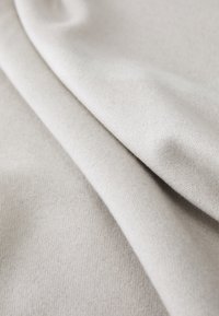 Light gray fabric draped in folds, featuring a soft texture and even weave, highlighting a smooth surface with subtle variations.