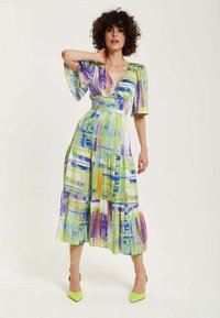 Flutter-sleeve dress in green fabric featuring a colorful abstract print with purple, blue, and orange accents. Knee-length tiered design.