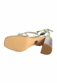 Sølvmetallic højhælede sandaler med dekorativ rem og rhinsten. Har en chunky hæl med en struktureret, beige gummisål.