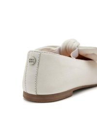 Scarpa piatta in pelle bianca con punta arrotondata e morbida lavorazione arricciata sulla parte anteriore, caratterizzata da un piccolo logo metallico sul retro.