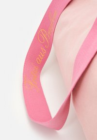 Roze stoffen lint met gouden cursieve tekst "Fritzi aus Preußen", met een zachte textuur en een gladde afwerking, gekruld aan de randen.
