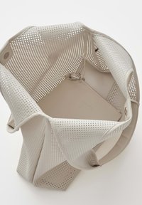 Weiße, perforierte Tragetasche mit geräumigem Innenraum und angebrachtem kleinen Beutel mit Reißverschluss und Schlüsselclip.