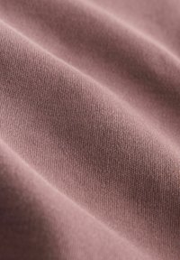 Svijetla mauve tkanina s finom, glatkom teksturom i suptilnim rastezanjem, prikazuje meku, ujednačenu površinu bez uzoraka ili akcenata.
