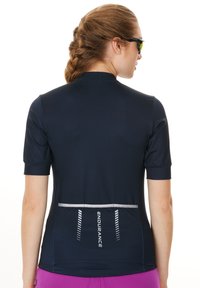 Kortærmet cykeltrøje i marineblå med en reflekterende baglomme, struktureret stof og blå syninger. Ideel til sportstøj.