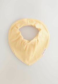 Babero para bebé a cuadros amarillos y blancos con cierre de broche y etiqueta "días felices" sobre un fondo claro.