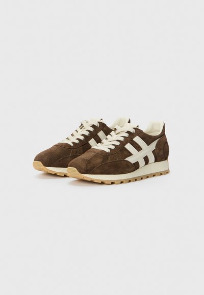Braune Wildleder-Turnschuhe mit beigen Netzeinsätzen, weißen StreifenDetails, runder Spitze und einer strukturierten Gummisohle.