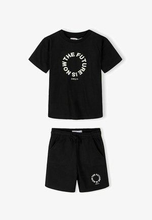 Sort skjorte med korte ærmer og shorts sæt med hvid cirkulær tekst, der siger "THE FUTURE IS NOW", og små japanske tegn nedenunder.