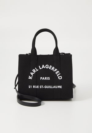 Zwarte rechthoekige handtas met twee handvatten en een afneembare riem, met witte tekst "KARL LAGERFELD PARIS 21 RUE ST-GUILLAUME" aan de voorkant.