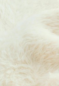 Miękka, puszysta tkanina w odcieniu off-white z długim, teksturowanym włosem, tworząca przytulny i zapraszający wygląd, idealna do tapicerki lub dekoracji.