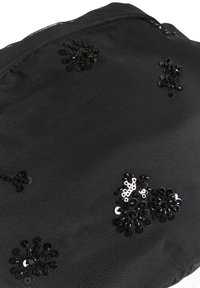 Fekete, textúrált anyag, amely díszes gyöngyökkel formáz virágos mintákat. Cipzáras zárás a felső szélen. Kompakt és könnyű kialakítás.