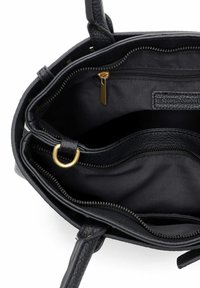 Sort lædertaskeinteriør med flere rum, guldfarvet lynlås og en blød stofforing med synligt mærkelabel.