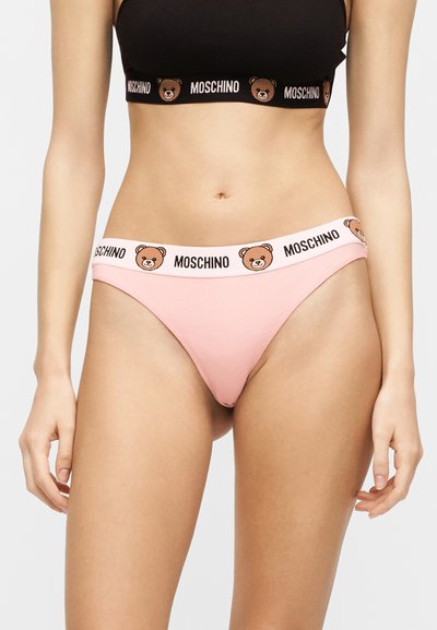 Γυναίκα που φοράει ροζ κάτω μέρος μπικίνι και μαύρο αθλητικό σουτιέν, και τα δύο με το λογότυπο Moschino και σχέδιο προσώπου αρκουδάκι στη μέση.