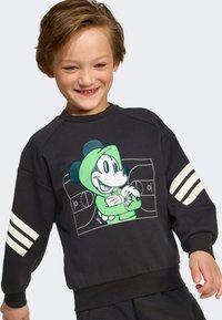 Čierna mikina s predným grafickým motívom zeleného Mickey Mouse. Obsahuje biele trojprúžkové akcenty na rukávoch a rebrované manžety.