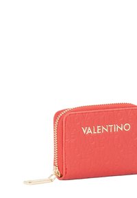 Monedero rojo con cierre de cremallera, material texturizado, logo en relieve, herrajes dorados, forma rectangular, diseño compacto con detalles visibles de costura.