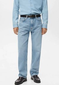 Vaqueros de mezclilla azul claro con corte recto, cinco bolsillos y acabado ligeramente desgastado, combinados con un cinturón y zapatos de cuero negro.