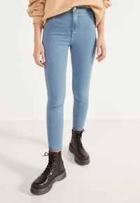 Ljusblå, högmidjade skinny jeans med en mjuk textur, kombinerat med svarta snörkängor med tjock sula.