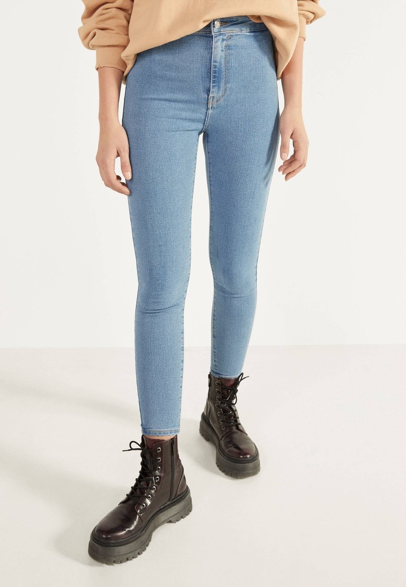 Ljusblå, högmidjade skinny jeans med en mjuk textur, kombinerat med svarta snörkängor med tjock sula.