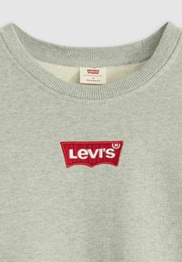Sweatshirt gris en coton, avec un col rond. Logo Levi's brodé rouge notable sur la poitrine. Étiqueté "coupe décontractée".