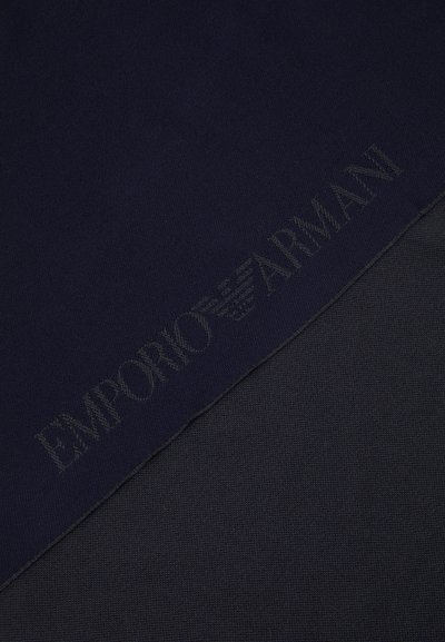 Maglione blu navy con una lavorazione a maglia testurizzata, caratterizzato da un logo discreto lungo l'orlo. Tessuto morbido con una sezione più scura in contrasto sotto.