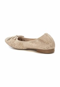 Bailarina beige de ante perforado con puntera redonda, detalle de lazo en la parte delantera y suela baja y flexible.