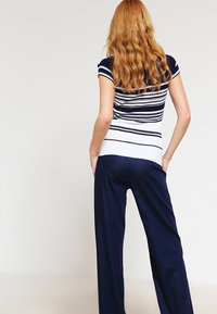 Marinblå och vitrandig kortärmad topp ihop med marinblå vida byxor. Toppen har ribbad textur och figurnära design.