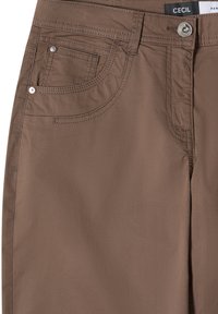Pantalon marron avec fermeture à boutons sur le devant, passants visibles et deux poches avant avec détails de couture.